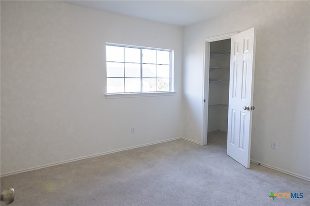 unfurnished bedroom with a closet, a spacious closet, and light colored carpet