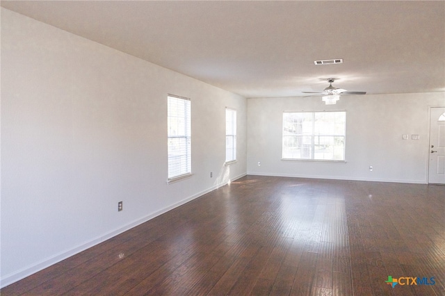 spare room featuring dark wood-type flooring, a wealth of natural light, and ceiling fan