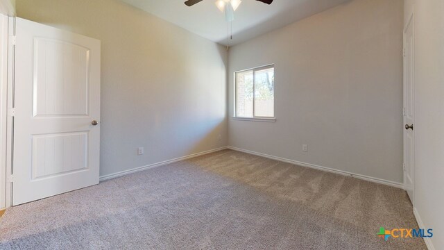 carpeted spare room featuring a ceiling fan and baseboards