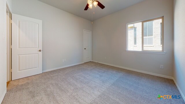 carpeted empty room featuring baseboards and a ceiling fan