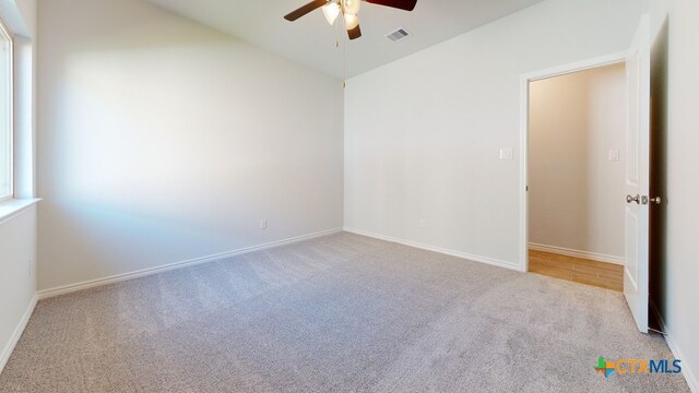 carpeted empty room with a ceiling fan, baseboards, lofted ceiling, and visible vents