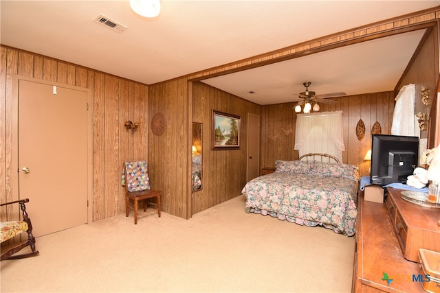 bedroom featuring wood walls, ceiling fan, and carpet floors