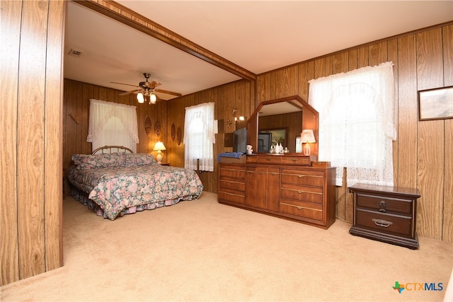 bedroom with wood walls, light colored carpet, ceiling fan, and beam ceiling