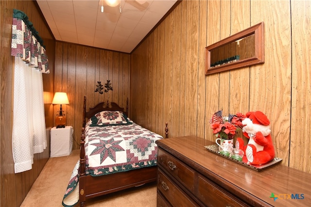 carpeted bedroom featuring wood walls and ceiling fan