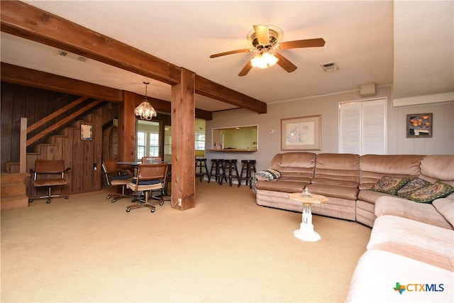 living room featuring beamed ceiling, ceiling fan with notable chandelier, wooden walls, and carpet floors