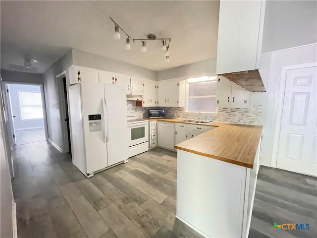 348 N Burke St, Goliad, TX 77963 - kitchen with a peninsula, white appliances, white cabinetry, tasteful backsplash, and a sink