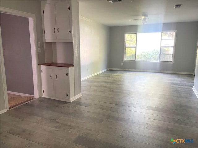 348 N Burke St, Goliad, TX 77963 - unfurnished dining area with baseboards, ceiling fan, hardwood / wood-style floors, and visible vents