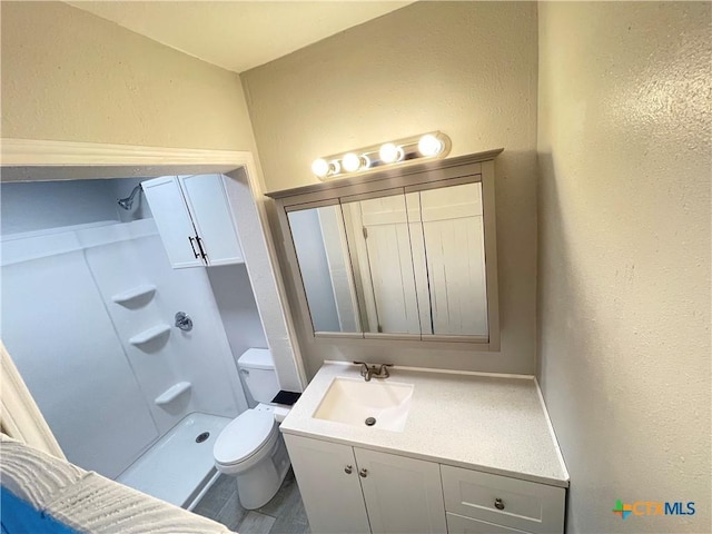 348 N Burke St, Goliad, TX 77963 - bathroom with vanity, a textured wall, toilet, and a shower stall