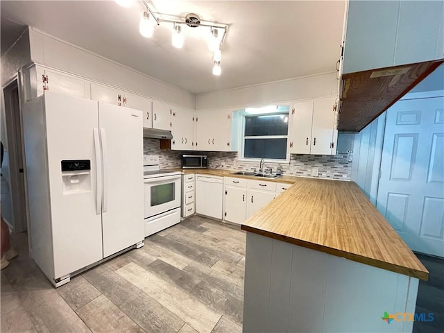 348 N Burke St, Goliad, TX 77963 - kitchen with wood finished floors, a sink, a peninsula, under cabinet range hood, and white appliances