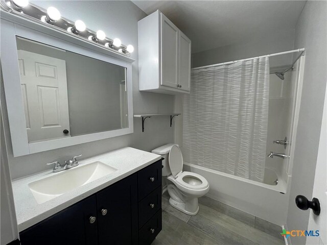 348 N Burke St, Goliad, TX 77963 - bathroom with vanity, toilet, wood finished floors, and shower / tub combo with curtain