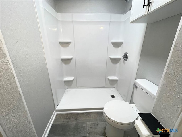 348 N Burke St, Goliad, TX 77963 - full bathroom featuring a textured wall, a shower, and toilet