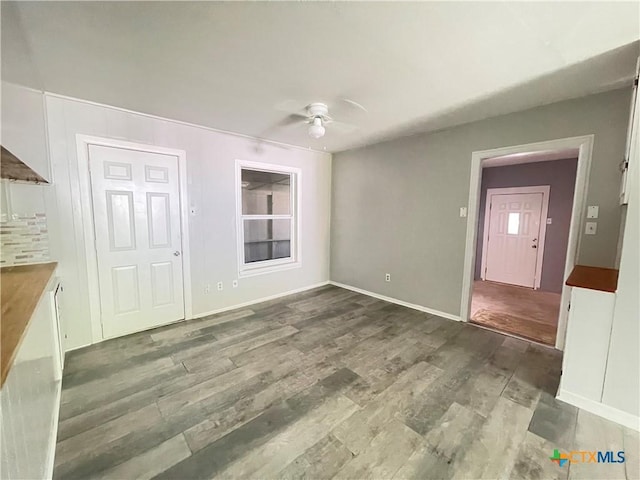 348 N Burke St, Goliad, TX 77963 - unfurnished living room with a ceiling fan, baseboards, and wood finished floors
