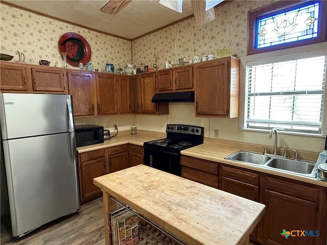 202 S Virginia St, Port Lavaca, TX 77979 - kitchen featuring black appliances, light countertops, wallpapered walls, under cabinet range hood, and light wood-type flooring