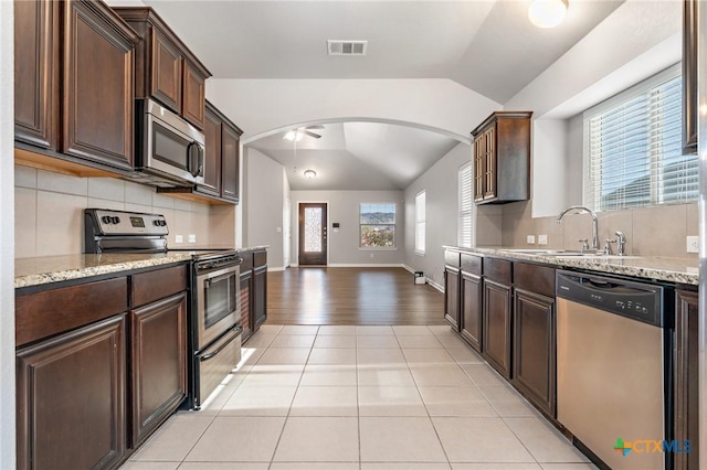 kitchen with visible vents, a sink, backsplash, appliances with stainless steel finishes, and lofted ceiling