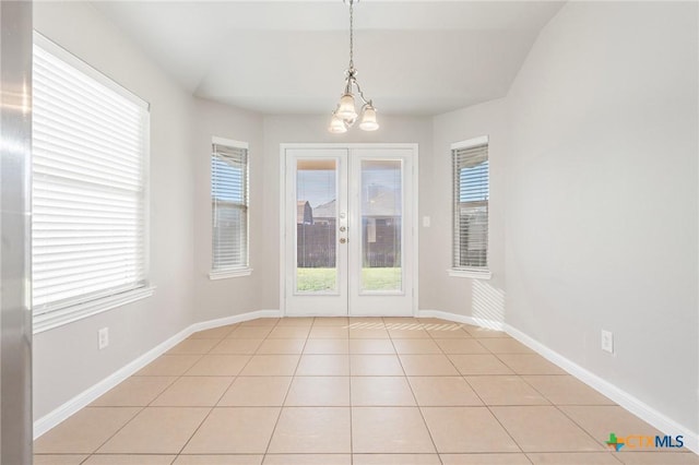 unfurnished dining area featuring light tile patterned floors, french doors, baseboards, and a notable chandelier