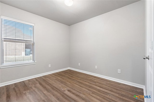 unfurnished room with dark wood finished floors and baseboards