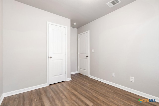 unfurnished room with visible vents, baseboards, and wood finished floors