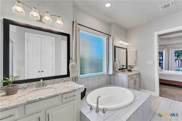 bathroom featuring tile patterned floors, vanity, a wealth of natural light, and tiled bath