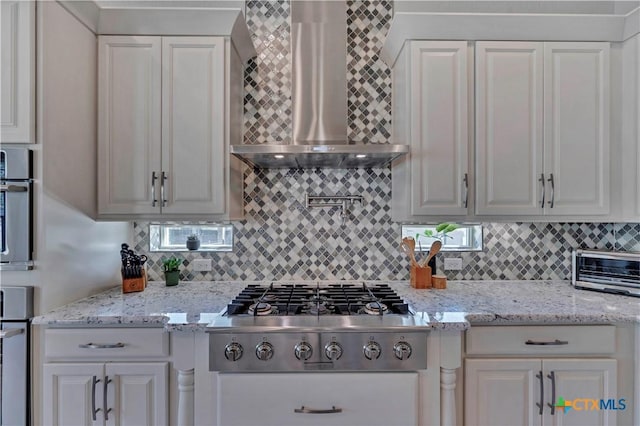 kitchen featuring wall chimney exhaust hood, white cabinetry, backsplash, and stainless steel gas cooktop