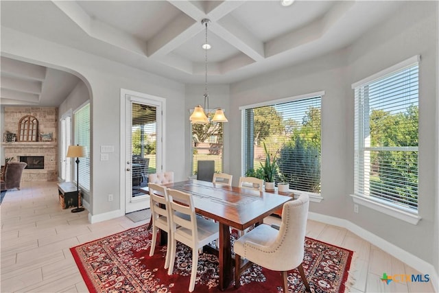 dining area featuring a large fireplace, beam ceiling, a wealth of natural light, and coffered ceiling