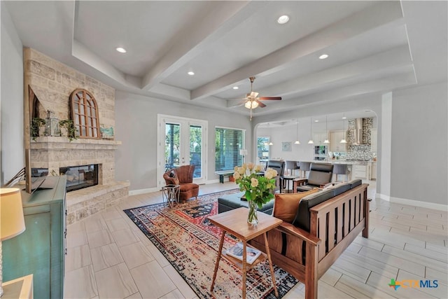 living room featuring ceiling fan, beam ceiling, a fireplace, and french doors