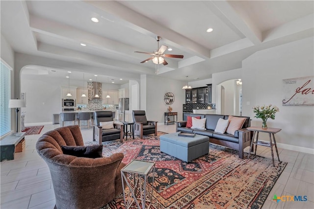 living room featuring ceiling fan with notable chandelier and beam ceiling