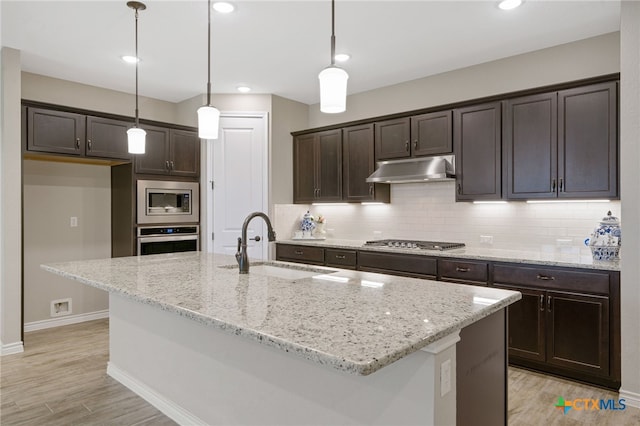 kitchen with decorative light fixtures, an island with sink, and stainless steel appliances