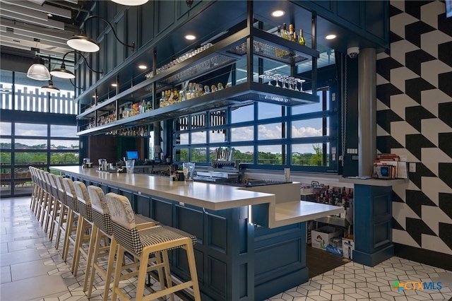 bar featuring a towering ceiling and blue cabinetry