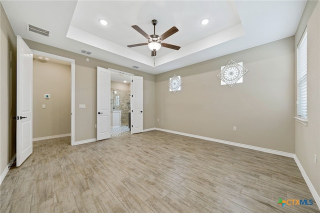 unfurnished bedroom featuring light wood-type flooring, ceiling fan, and a raised ceiling