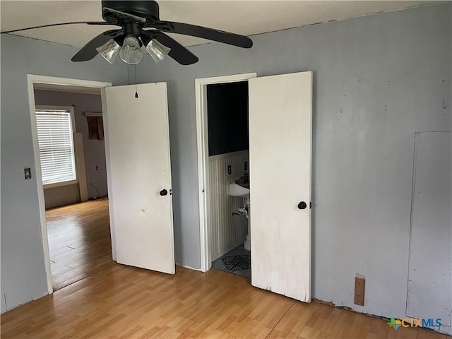 unfurnished bedroom with ensuite bath, ceiling fan, and light hardwood / wood-style floors