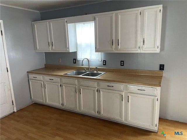 kitchen with white cabinetry, sink, and light hardwood / wood-style floors