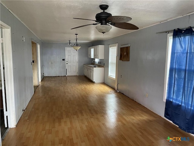 unfurnished living room featuring light hardwood / wood-style flooring, ceiling fan, and sink