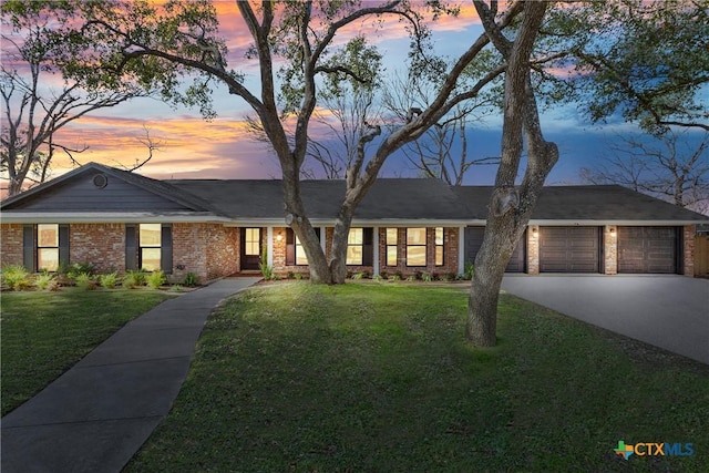 single story home featuring a garage and a lawn