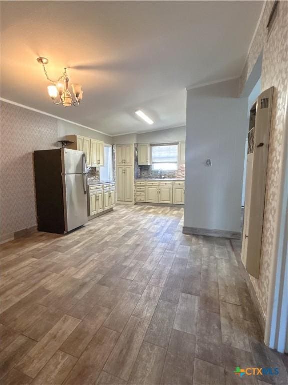 3101 Bobolink Ln, Victoria, TX 77901 - kitchen featuring freestanding refrigerator, cream cabinetry, wallpapered walls, a chandelier, and wood finished floors