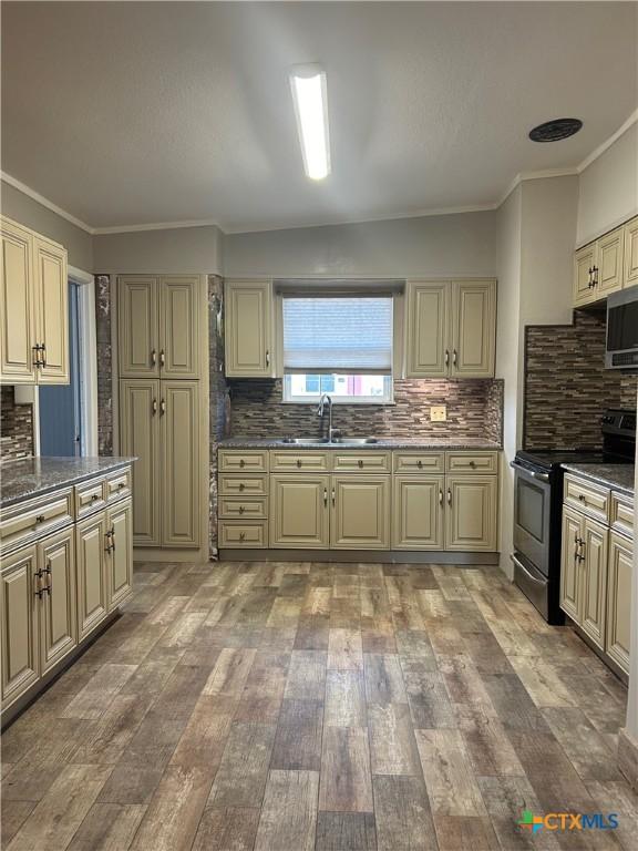 3101 Bobolink Ln, Victoria, TX 77901 - kitchen featuring stainless steel appliances, cream cabinetry, tasteful backsplash, light wood-type flooring, and crown molding