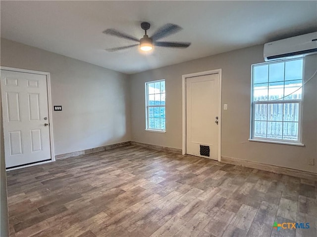 foyer entrance featuring an AC wall unit, ceiling fan, plenty of natural light, and hardwood / wood-style flooring