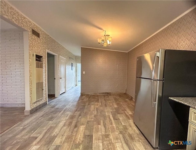 kitchen with a notable chandelier, crown molding, stainless steel refrigerator, and light hardwood / wood-style flooring