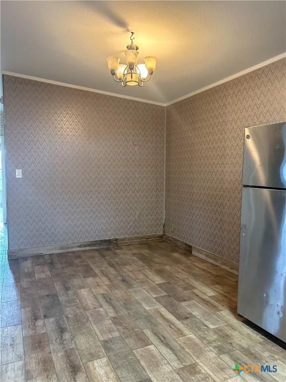 3101 Bobolink Ln, Victoria, TX 77901 - unfurnished dining area featuring crown molding, a chandelier, wood finished floors, and wallpapered walls