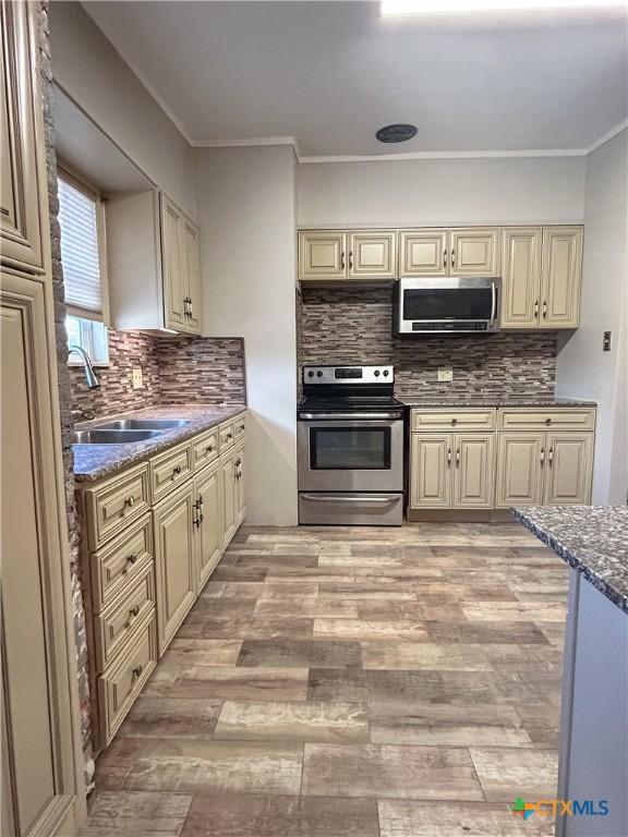 kitchen featuring tasteful backsplash, dark stone countertops, crown molding, and stainless steel appliances