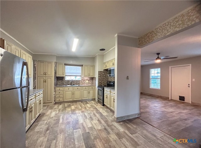 3101 Bobolink Ln, Victoria, TX 77901 - kitchen featuring stainless steel appliances, cream cabinets, light wood-style floors, plenty of natural light, and crown molding