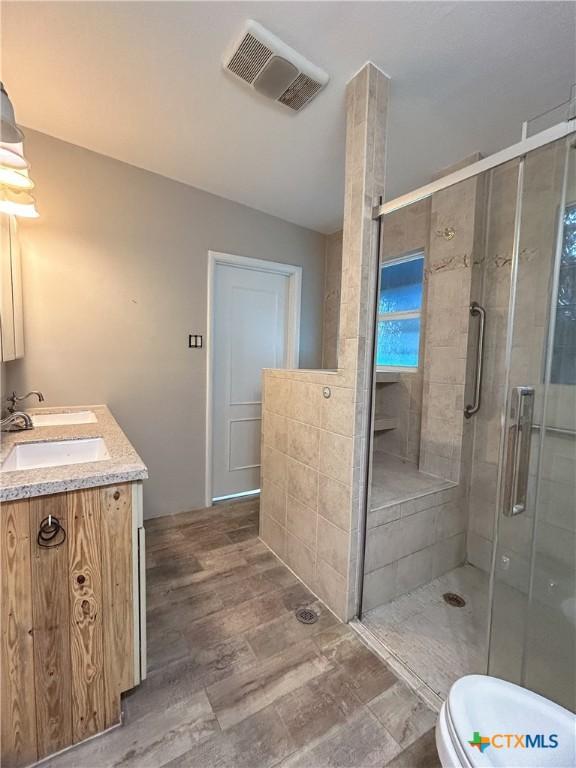 bathroom featuring wood-type flooring, vanity, toilet, and an enclosed shower