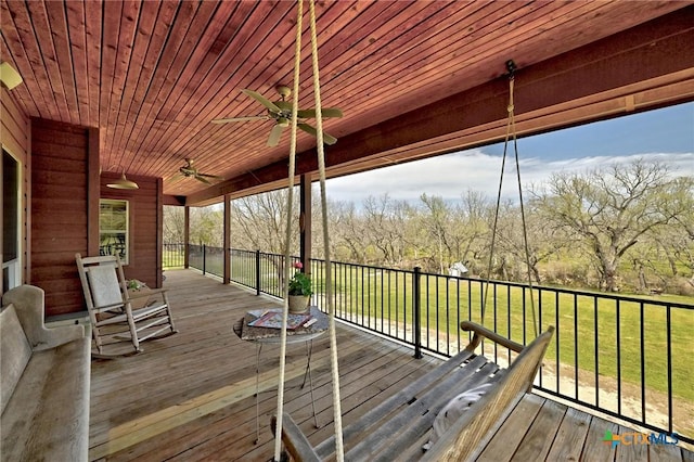 wooden terrace with a ceiling fan and a lawn