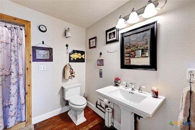 bathroom with a shower with shower curtain, baseboards, toilet, and wood finished floors