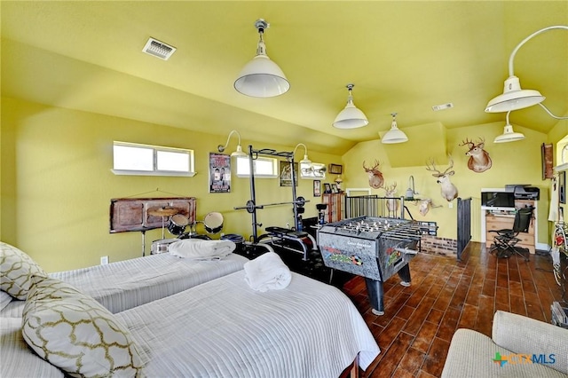 bedroom featuring wood finished floors, visible vents, and vaulted ceiling