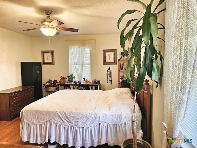 bedroom with ceiling fan, light hardwood / wood-style floors, and a textured ceiling