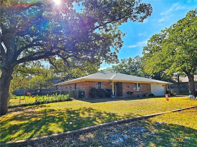 ranch-style house featuring a garage, brick siding, a front lawn, and fence