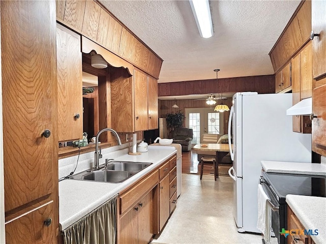 kitchen with stainless steel range with electric stovetop, a textured ceiling, wooden walls, sink, and pendant lighting