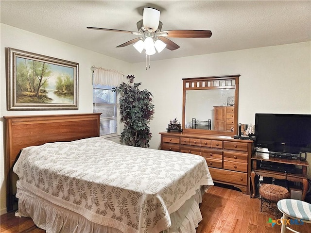 bedroom with ceiling fan, wood-type flooring, and a textured ceiling