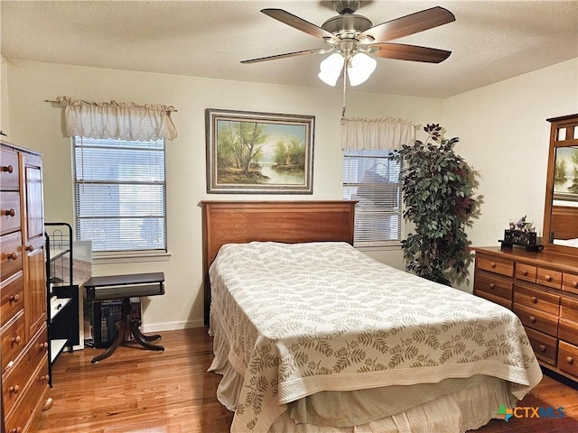 bedroom with hardwood / wood-style floors, a textured ceiling, multiple windows, and ceiling fan