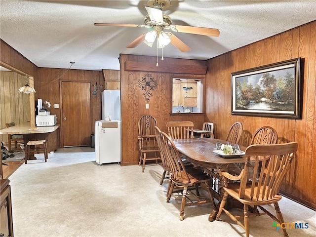 dining room with wooden walls, ceiling fan, and a textured ceiling